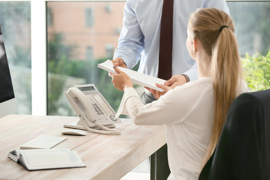 Beautiful female secretary working with colleague in office