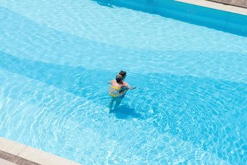 Aerial top view on the men and woman in the swimming pool with transparent blue water. in motion