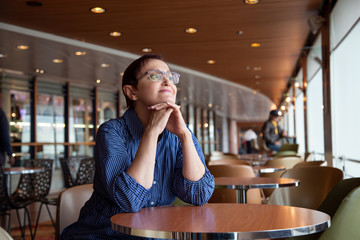 Nice portrait of a middle aged woman sitting at the table in a cafe alone and looking out to the window.