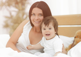 Portrait of a beautiful mother with her baby in the bedroom