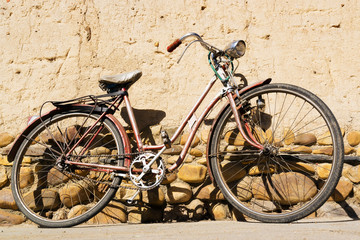 Fototapeta na wymiar old vintage red bike on mud wall