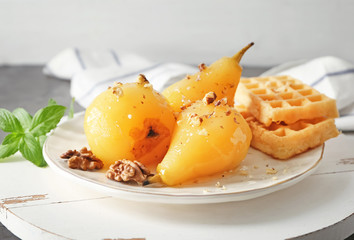 Plate with delicious poached pears in wine and waffles on plate