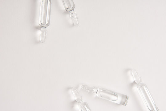elevated view of ampoules with medical liquid on white surface