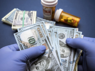 Doctor with blue latex gloves counting hundred dollar bills in a hospital
