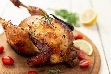 Roasted chicken with tomatoes on wooden cutting board