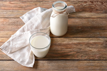 Glass and bottle of milk on wooden background