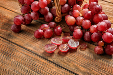 Wicker basket with red ripe grapes on wooden table