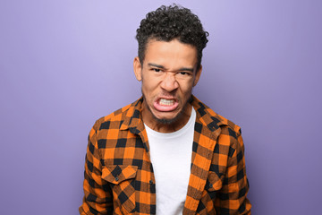 Portrait of aggressive African-American man on color background