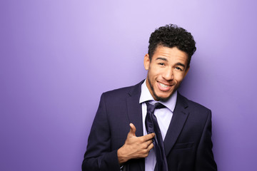 Portrait of happy African-American businessman on color background