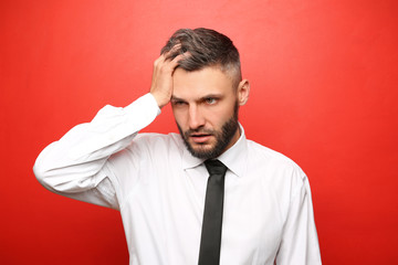 Portrait of tired businessman on color background