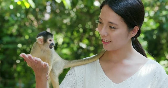 Woman feed Squirrel Monkey in zoo park