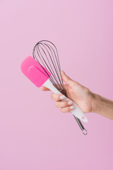 cropped shot of woman holding spatula and whisk isolated on pink