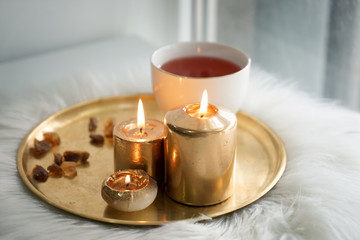 Beautiful burning candles with cup of aromatic tea on metal tray