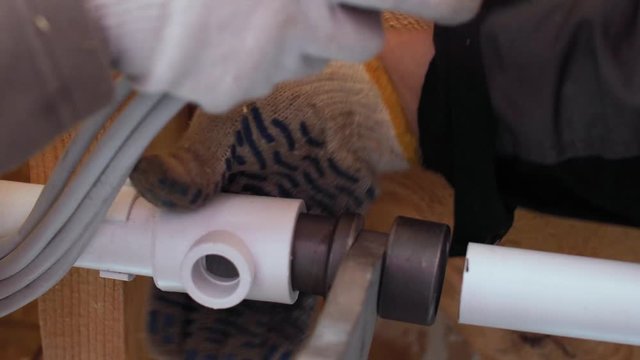 Hands in gloves soldering plastic pipes to connect them together. Plumbing work in the construction of a frame house. 4k 60fps slow motion.