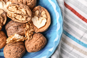 Plate with tasty walnuts on table, closeup