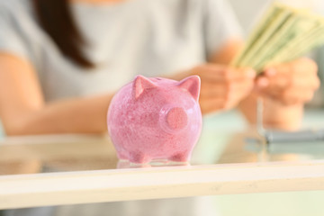 Obraz na płótnie Canvas Cute piggy bank on table of woman counting money
