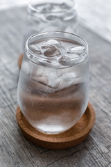 Glass of clean water and ice cubes on wooden table