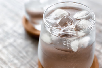 Glass of fresh water with ice cubes on table, closeup