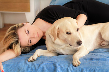 Woman with cute dogs at home. Handsome girl resting and sleeping with her dog in bed in bedroom. Owner and dog sleeping in sofa. Yellow labrador retriever relax. Portrait of woman and her best friend.