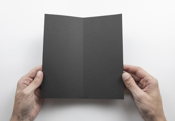 Mens hands holding black booklet