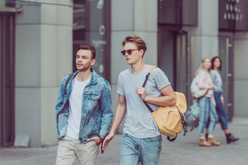 portrait of young travelers with backpacks walking on city street