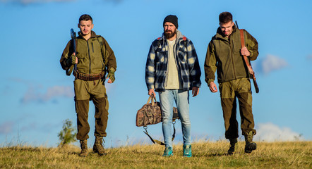 Group men hunters or gamekeepers nature background blue sky. Guys gathered for hunting. Men carry...