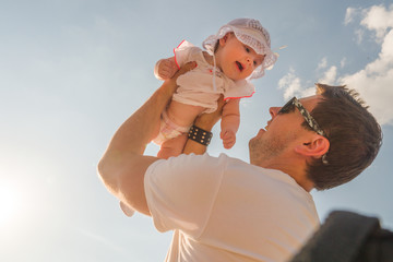 Dad holds a child over his head. Half a year old baby. Walk down the street.