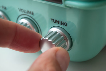 closeup of hand of man turning vintage fifties style radio buttons on white background