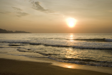 Naklejka na ściany i meble Golden orange sunset over ocean, small waves on sandy beach