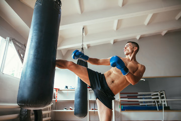 Male boxer workout high kick on the punching bag in gym