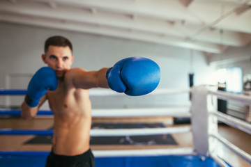 Fototapeta na wymiar Male boxer fighting in gym and making direct hit