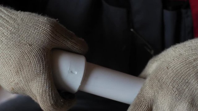Hands in gloves connect plastic pipes together. 4k 60fps slow motion. Brazing of pipes made of polycarbonate. Connection of water pipe parts.