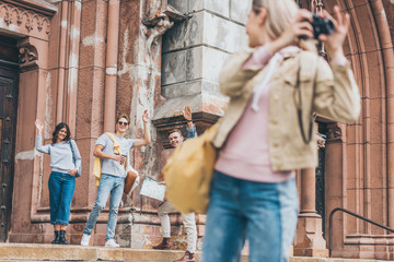 selective focus of friends waving to girl taking photo of city on camera