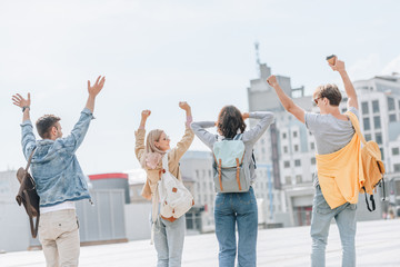 Obraz premium back view of young stylish tourists gesturing having fun and walking in city