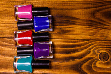 Different nail polishes on a wooden table. Top view