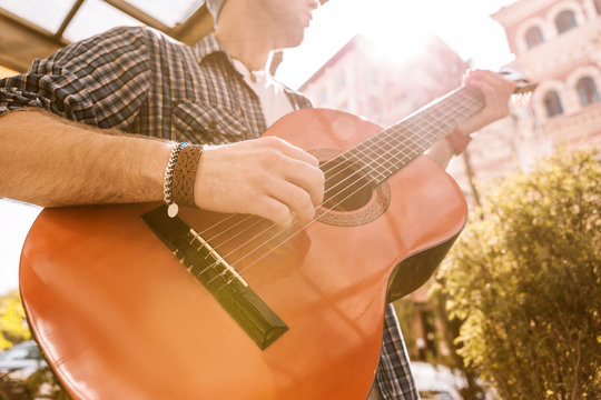 Favorite melody. Close up of male attractive hands picking strings and holding chord