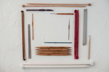 Variety of rochet hooks and knitting needles in different sizes on white background.