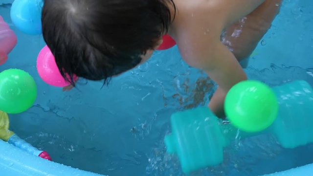 slow motion child playing water in baby inflatable pool