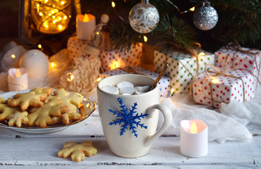 Fototapeta na wymiar Cup cocoa with marshmallow, homemade chocolate cookie and peanut biscuit, lighted candles, xmas tree decoration on wooden background. Christmas and New Year. Holiday celebration concept.