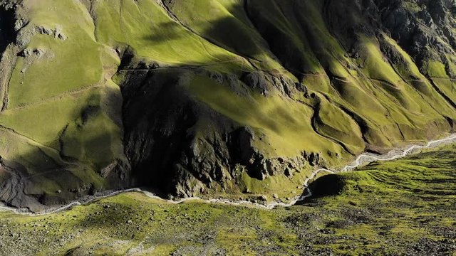 Arial view over the mountain river. Vertical panorama of the rocky wall of the ridge. Flying forward. North Caucasus. Russia