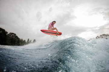 Teenager girl riding on the orange wakeboard