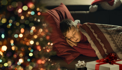 Cute boy waiting for Santa and sleeping on the sofa