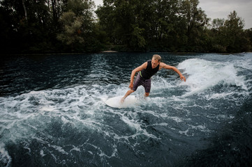 Active man riding on the wakeboard on the wave