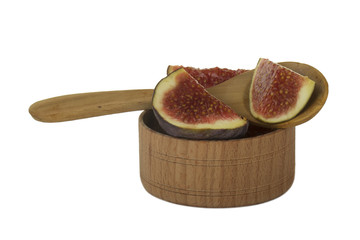 slices of purple fig with wooden spoon in wooden cup isolated on white background