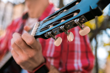 Elegant headstock. Close up of brown headstock and male hand touching guitar and playing for pleasure