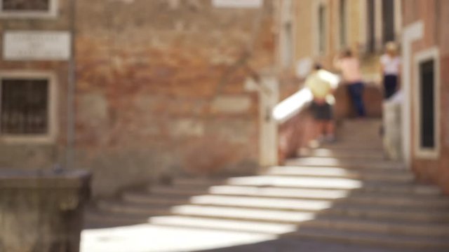 Exterior scene of tourists in Venice Italy walking up stairwell to look closer at buildings Blurred shot of people walking up old steps to traditional Venetian homes 4k