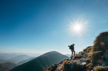 Boy backpacker traveler walk up on mountain top in contrast sun light