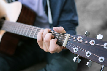 Playing the guitar. Close up of young boy wearing jeans and blue sport jacket playing the guitar...