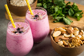 Glasses of berry smoothie with nuts, mint, blueberry, blackberry, raspberry, and yogurt on wooden table. Weight loss and diet concept. 