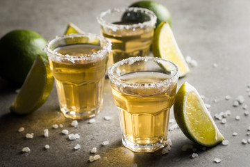 Macro photo of shots of gold Mexican tequila with lime and salt on wooden rustic background. Alcoholic drink concept. selective focus.